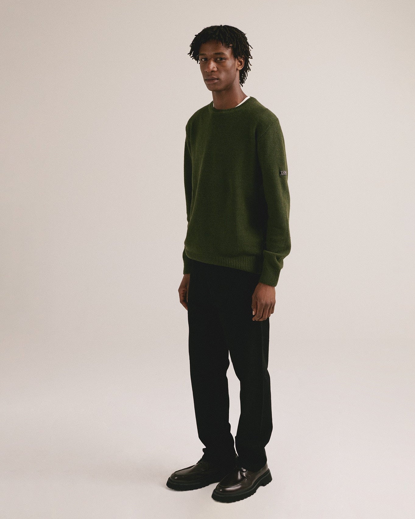 Modelo masculino con suéter de punto verde oliva de manga larga con diseño básico de IAIOS.