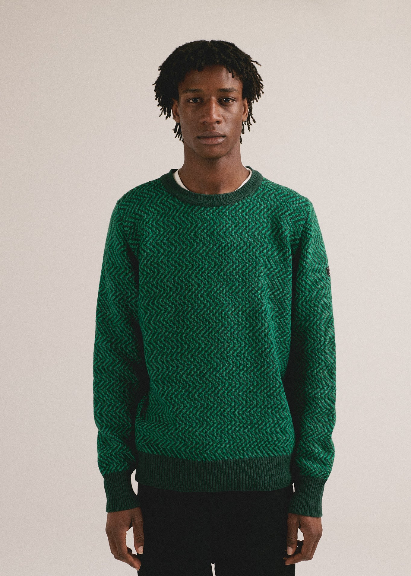 Hombre joven vistiendo jersey verde de punto con patrón texturizado y estilo casual moderno.