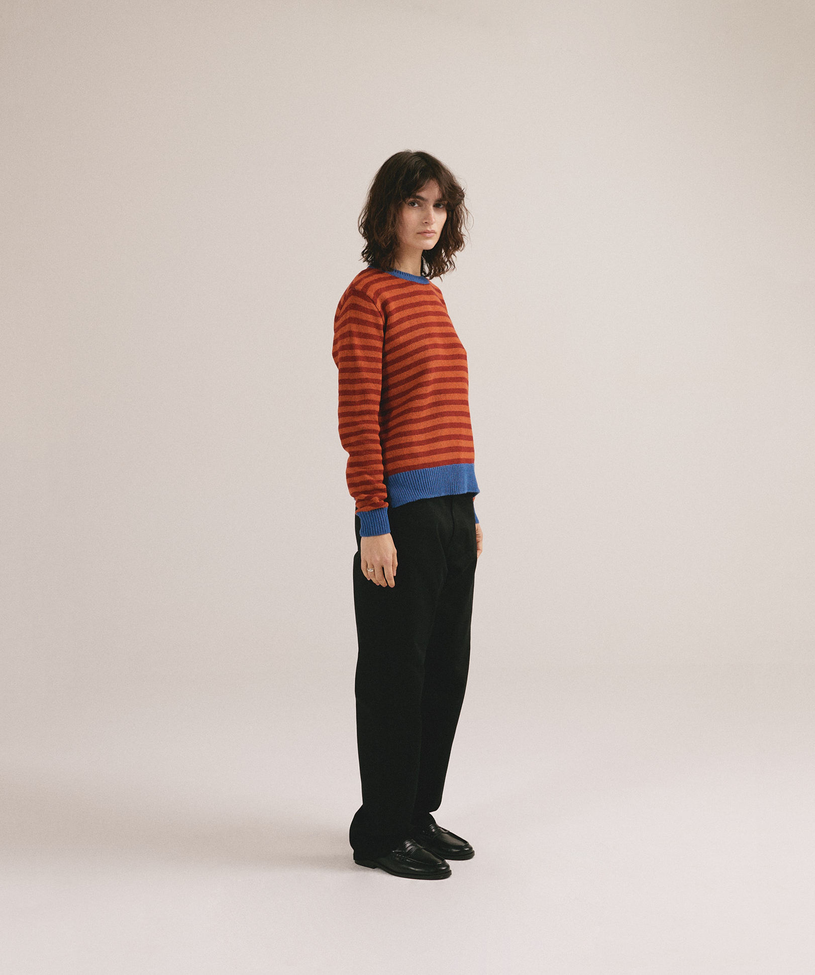 Mujer joven vistiendo jersey de punto a rayas rojo y naranja con estilo casual moderno.