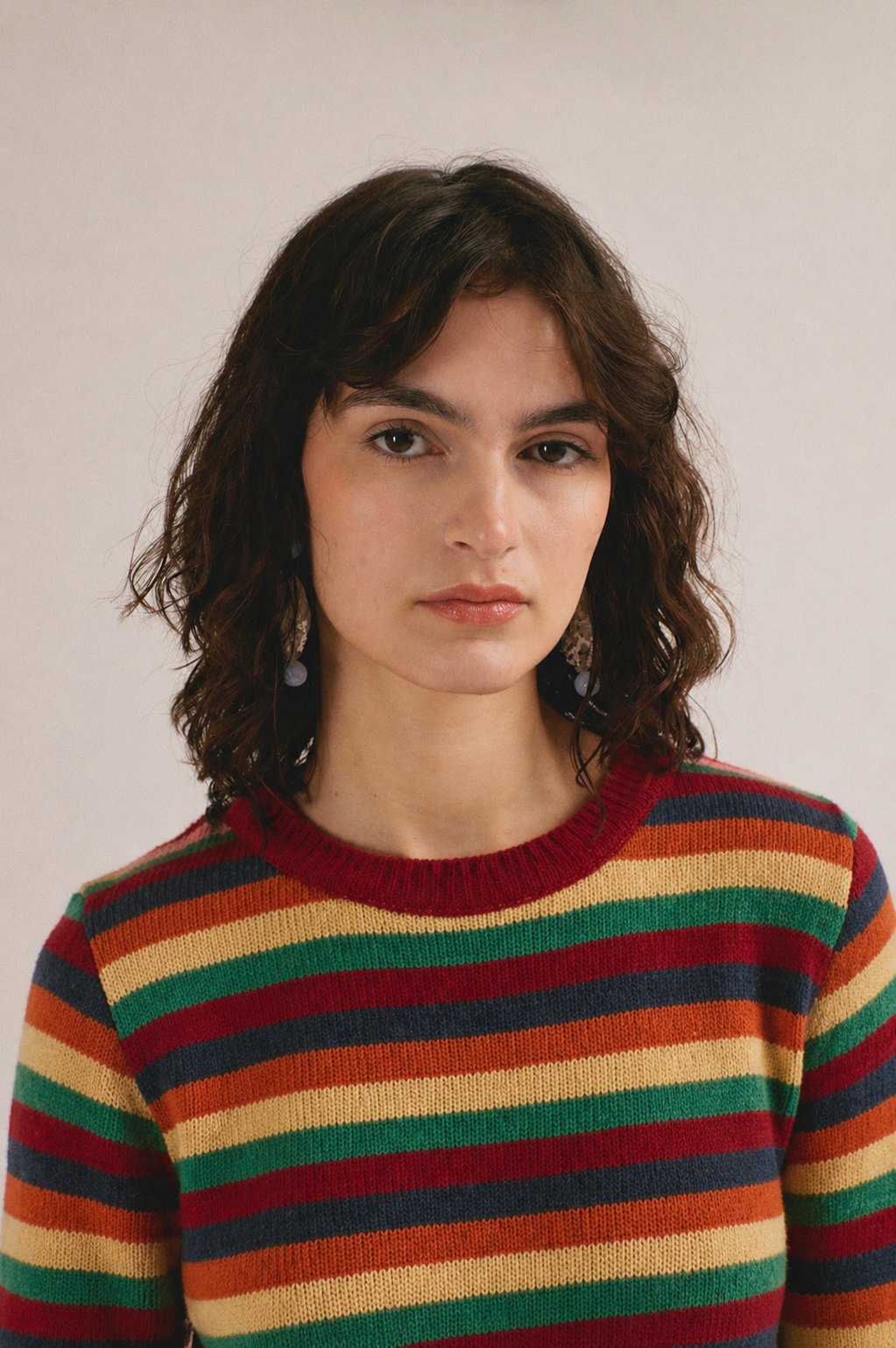 Modelo femenina con suéter de punto de rayas en tonos rojo, verde, amarillo y azul de IAIOS.