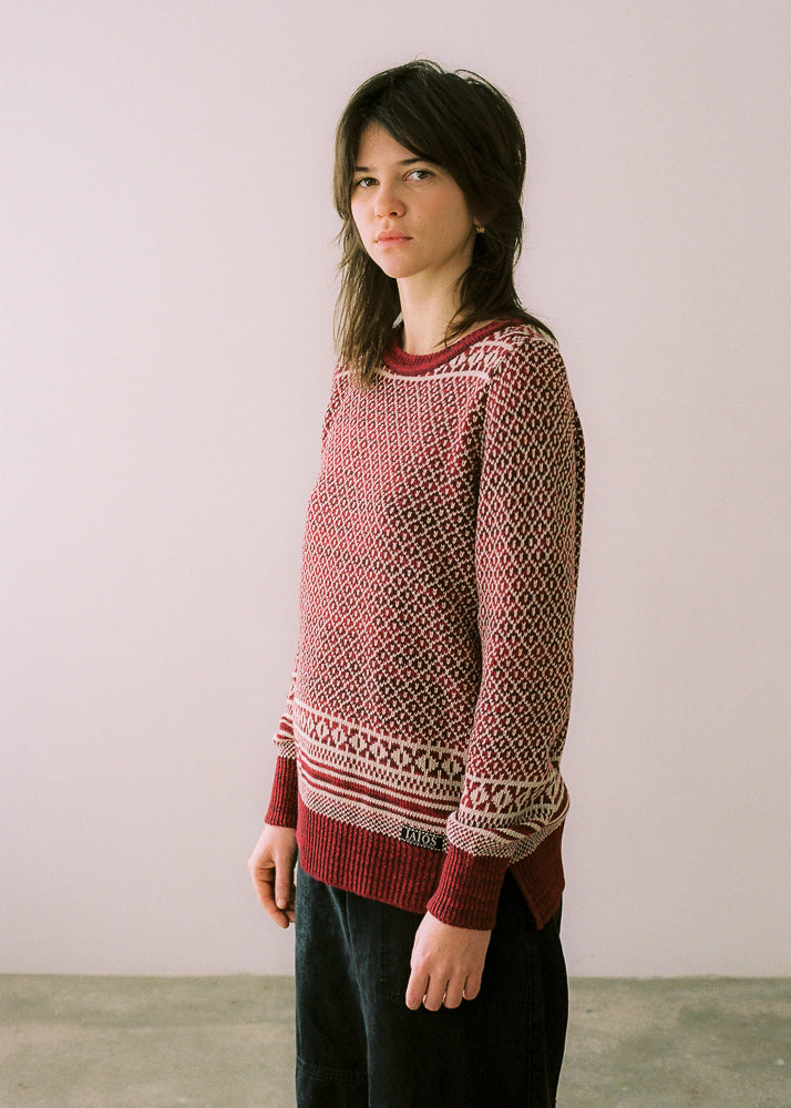 La modelo lleva el jersey de mujer IAIOS rojo y blanco con jacquard navideño, moda sostenible hecha en Catalunya (España) con hilo reciclado, ideal para invierno.