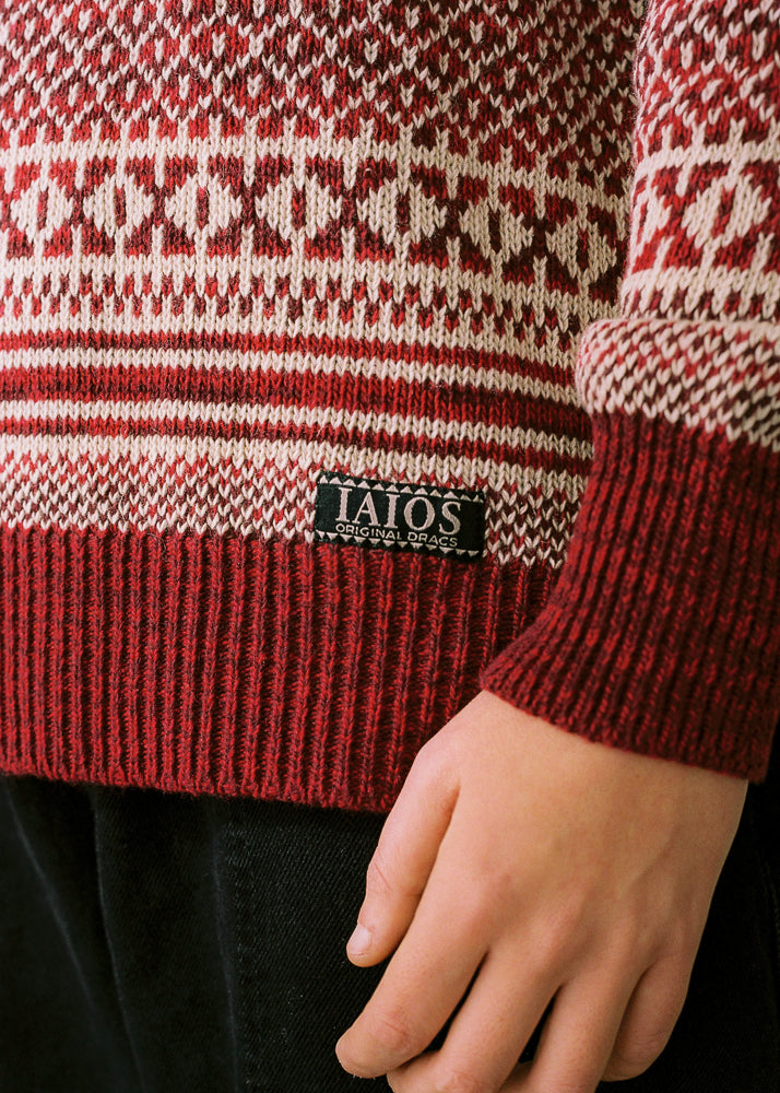 Fotografía de detalle donde se aprecia la posición de la etiqueta con el logo de IAIOS en la parte de la cadera. ersey de mujer IAIOS rojo y blanco con jacquard navideño, detalle del tejido, moda sostenible elaborada con hilo reciclado en talleres de Catalunya (España).