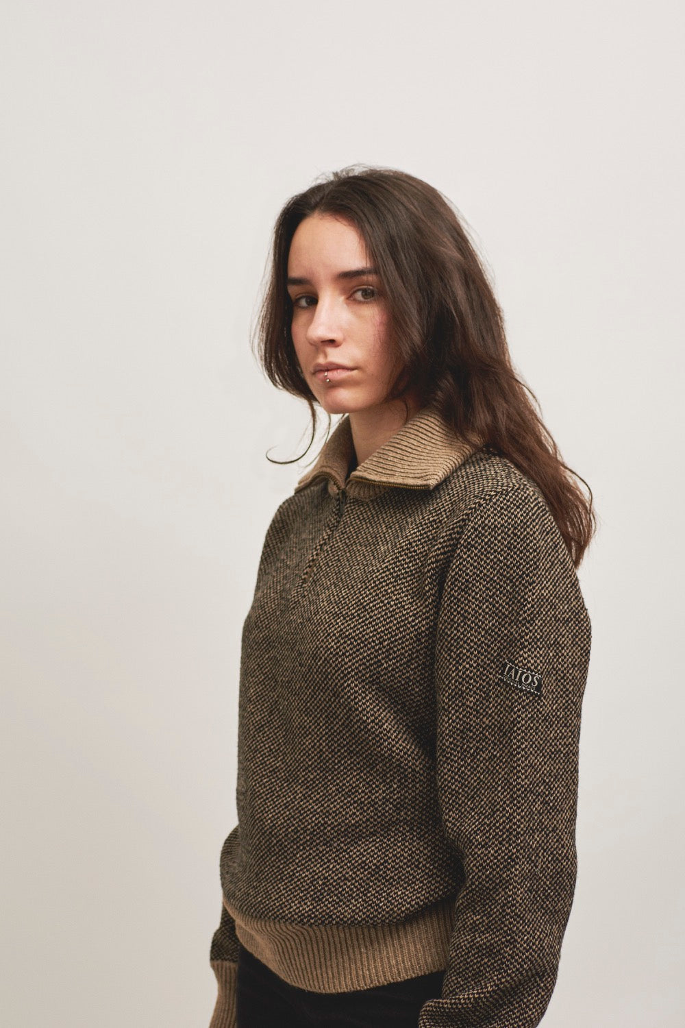 Modelo con jersey unisex IAIOS de punto nido de avispa en negro y beige con media cremallera, hecho en Catalunya (España) con hilo reciclado.