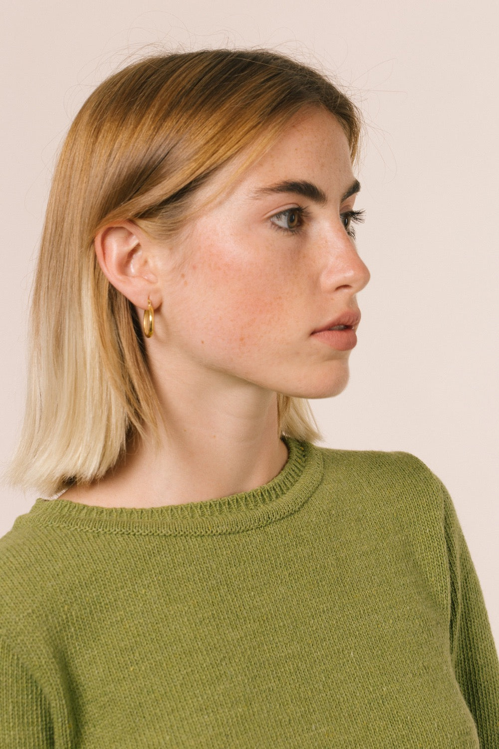 La modelo lleva el jersey de mujer IAIOS verde claro liso, patrón femenino básico y recto, moda sostenible hecha en Catalunya (España) con hilo reciclado, ideal para invierno.
