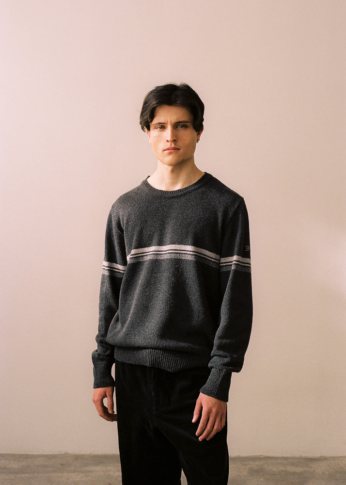 Fotografia de mig cos del model amb el jersei lloc combinat amb pantalons negres.