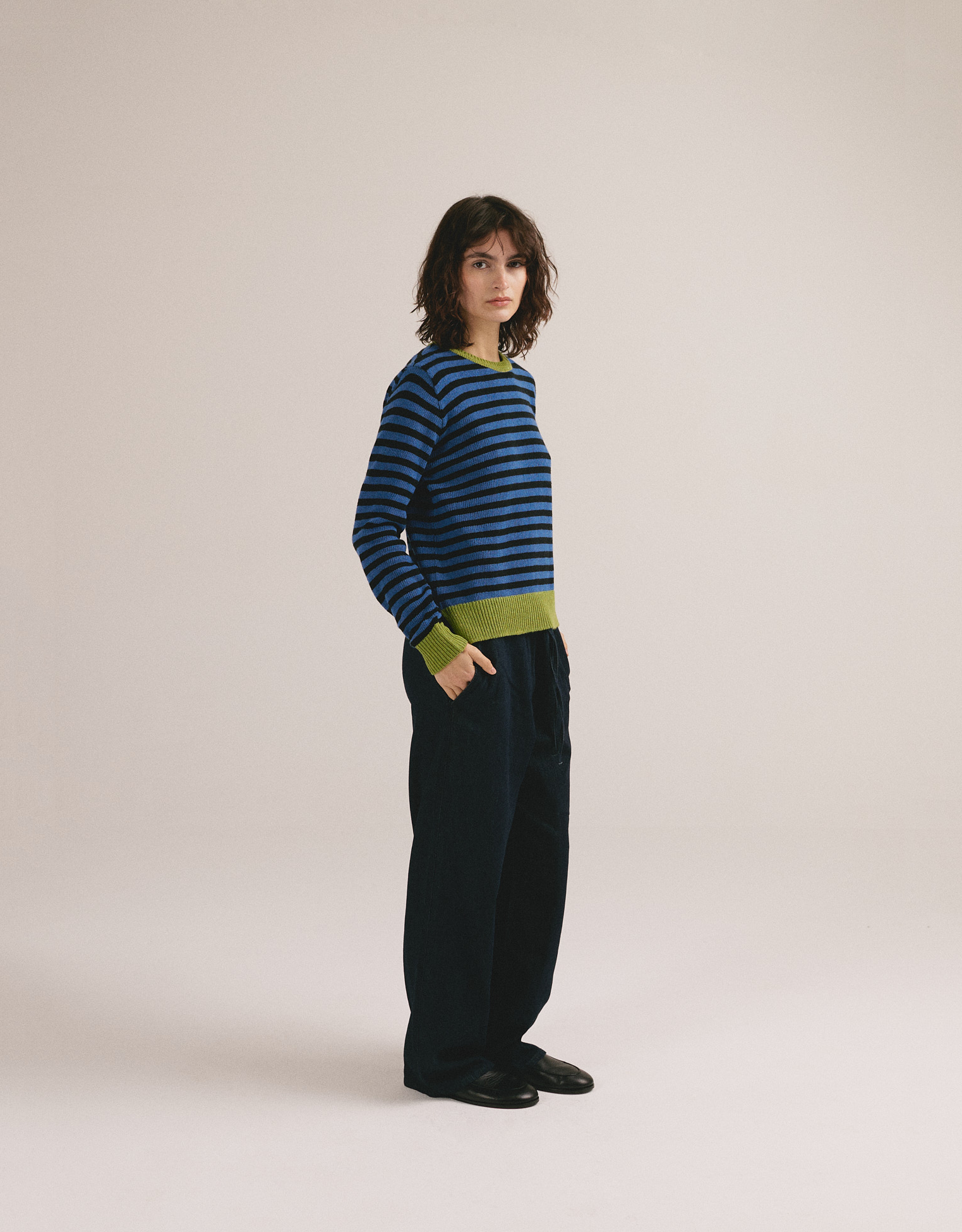 Modelo femenina con suéter de punto de rayas en azul y negro con cuello y puños verdes de IAIOS.