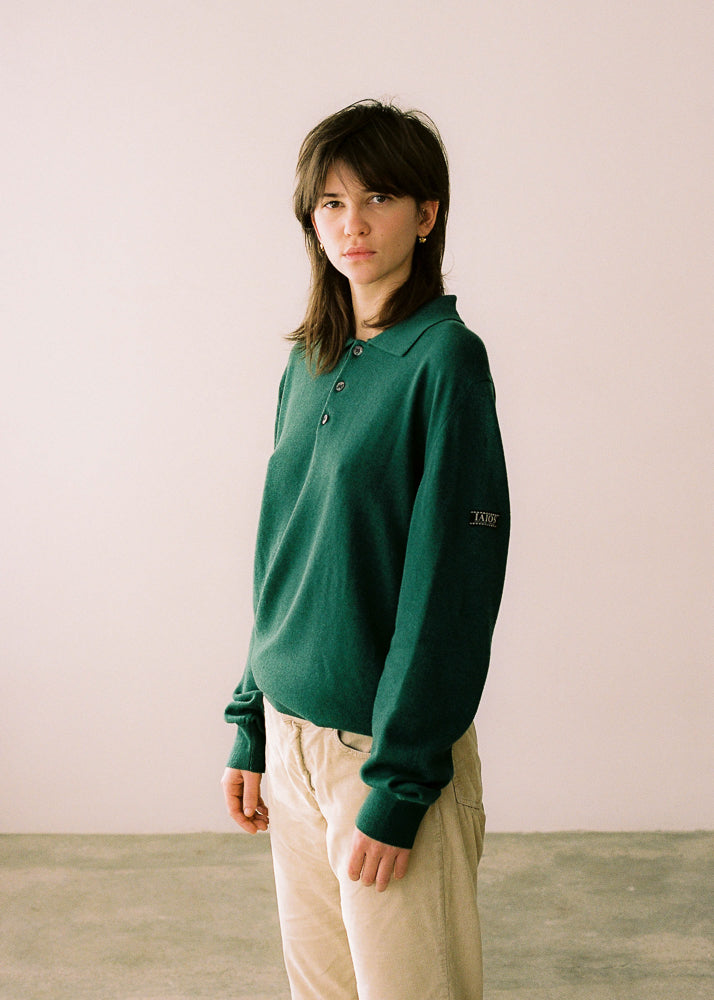 La modelo lleva el polo unisex IAIOS en color verde con cuello clásico y botones, confeccionado con algodón reciclado, moda sostenible hecha en Catalunya (España).