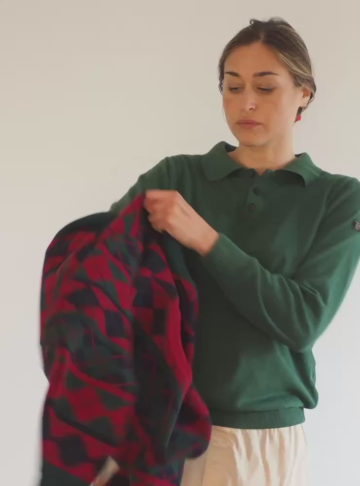 Modelo probando el jersey unisex IAIOS con diseño de rombos en tonos rojos, verdes y azul marino, tejido jacquard, hecho en Catalunya (España) con hilo reciclado.