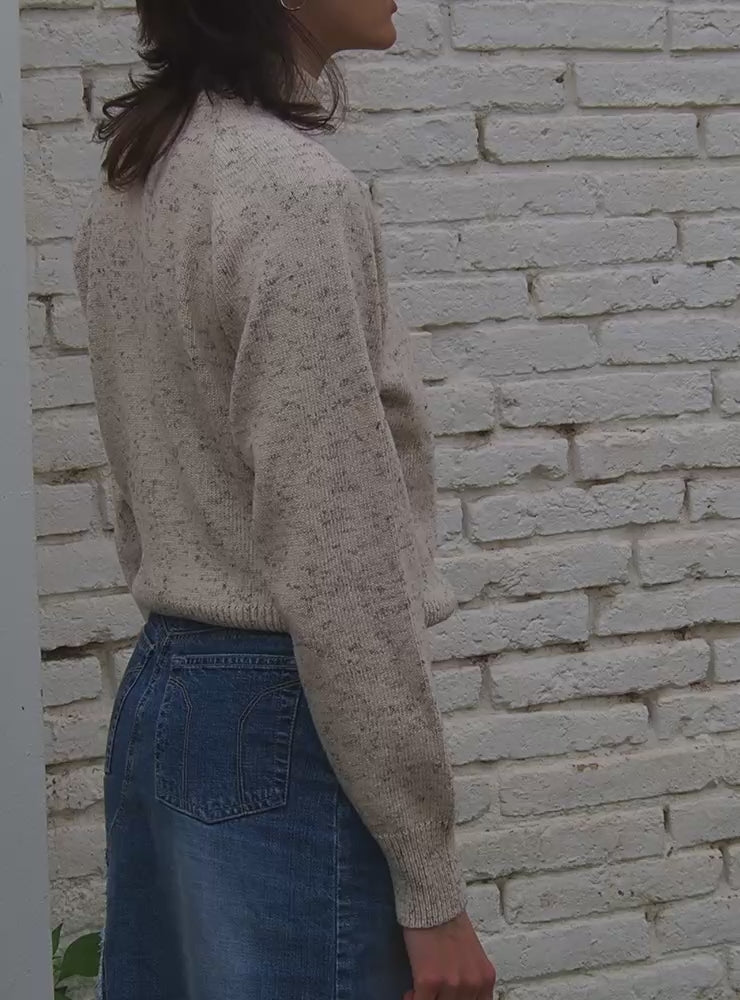 Modelo con el ersey sostenible IAIOS blanco jaspeado de cuello alto y detalles acanalados, hecho en Catalunya (España) con hilo reciclado, ideal para invierno.