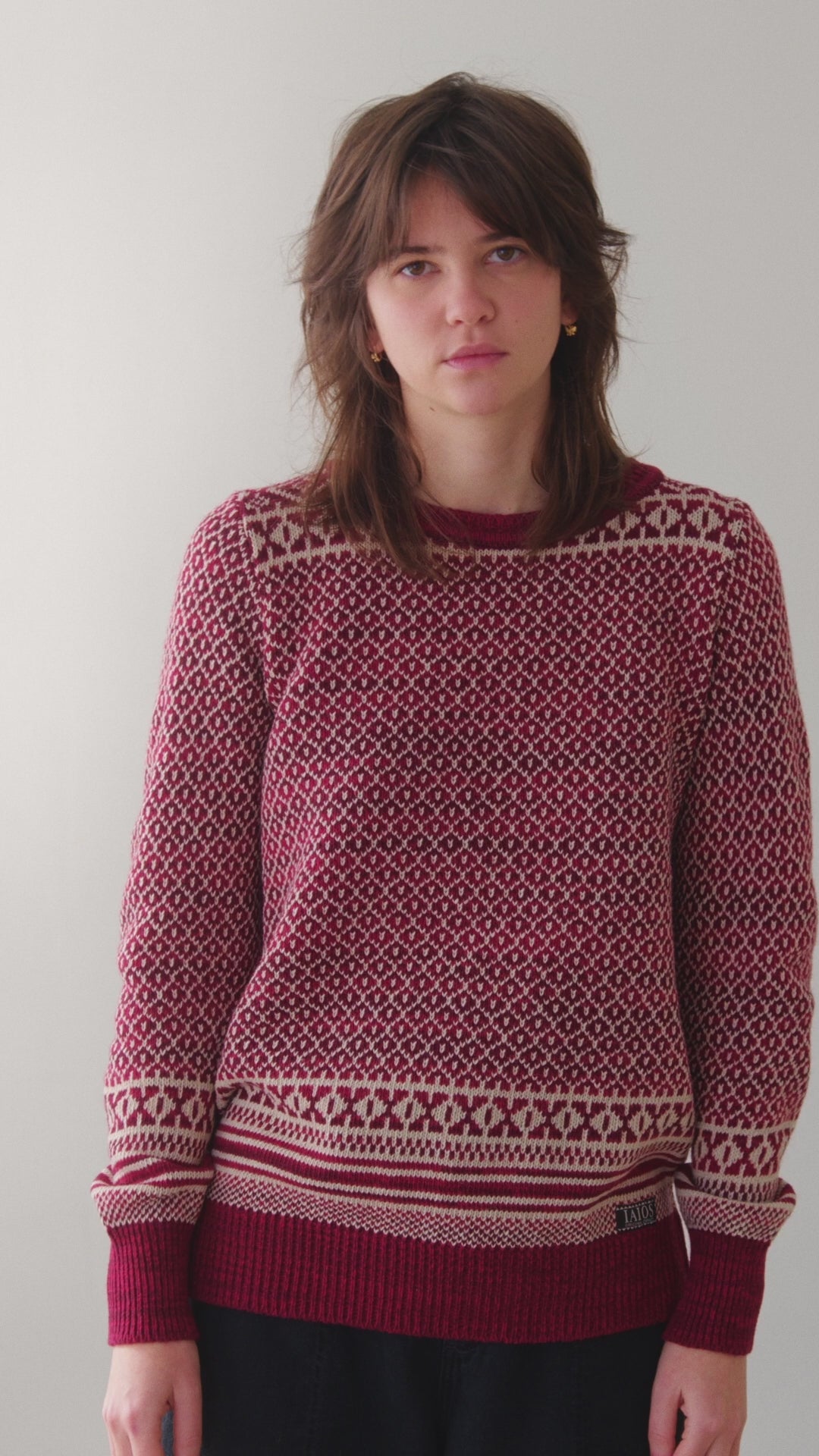 La modelo lleva el jersey de mujer IAIOS rojo y blanco con jacquard navideño, moda sostenible hecha en Catalunya (España) con hilo reciclado, ideal para invierno.