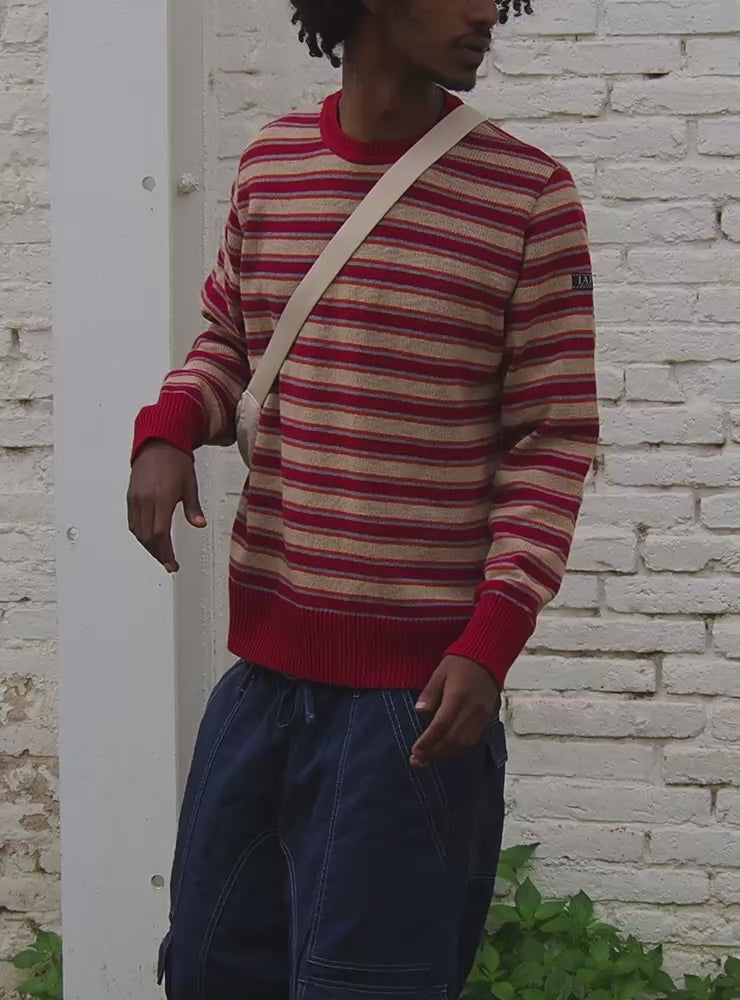 Video del modelo lleva el jersey IAIOS unisex de rayas rojas, beige y naranjas, con cuello redondo y ajuste clásico, tejido con hilo reciclado en talleres de Catalunya (España).