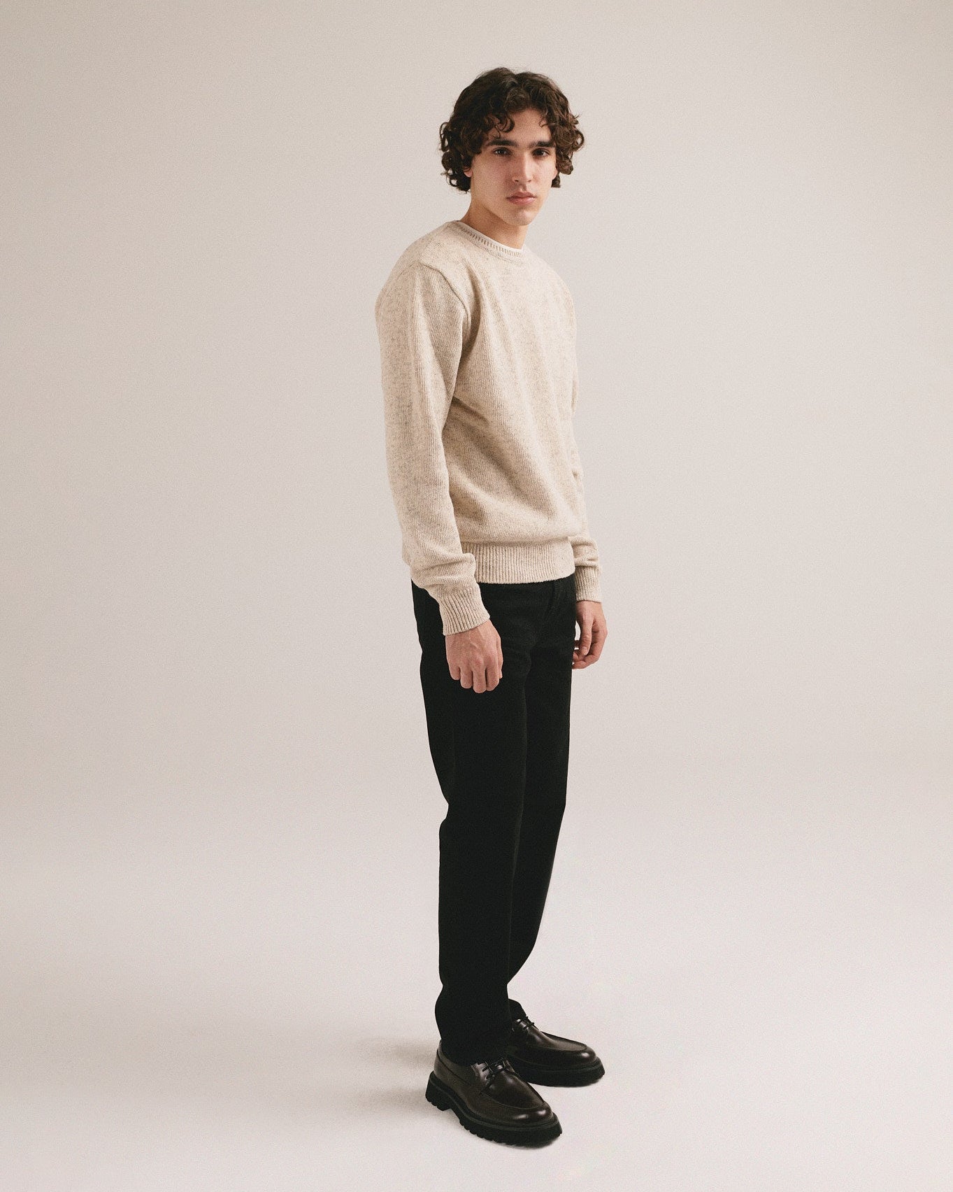Hombre joven vistiendo jersey blanco espigado de punto con estilo minimalista y look casual moderno.