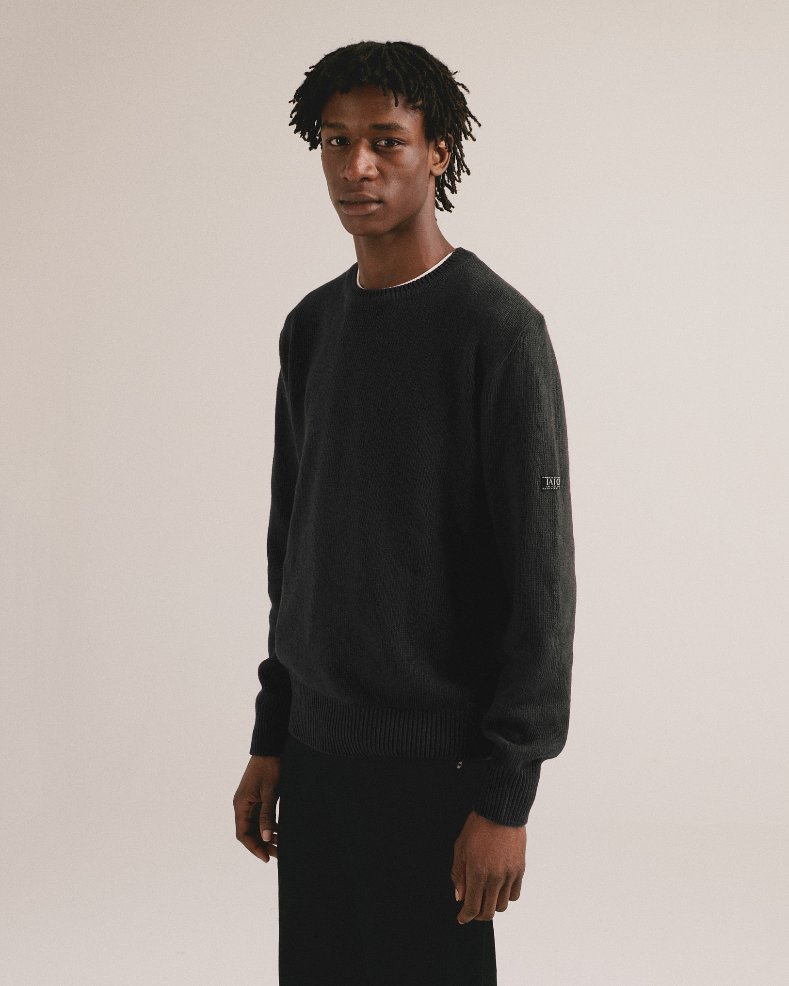 Modelo masculino con suéter de punto negro grafito de manga larga con diseño básico de IAIOS.