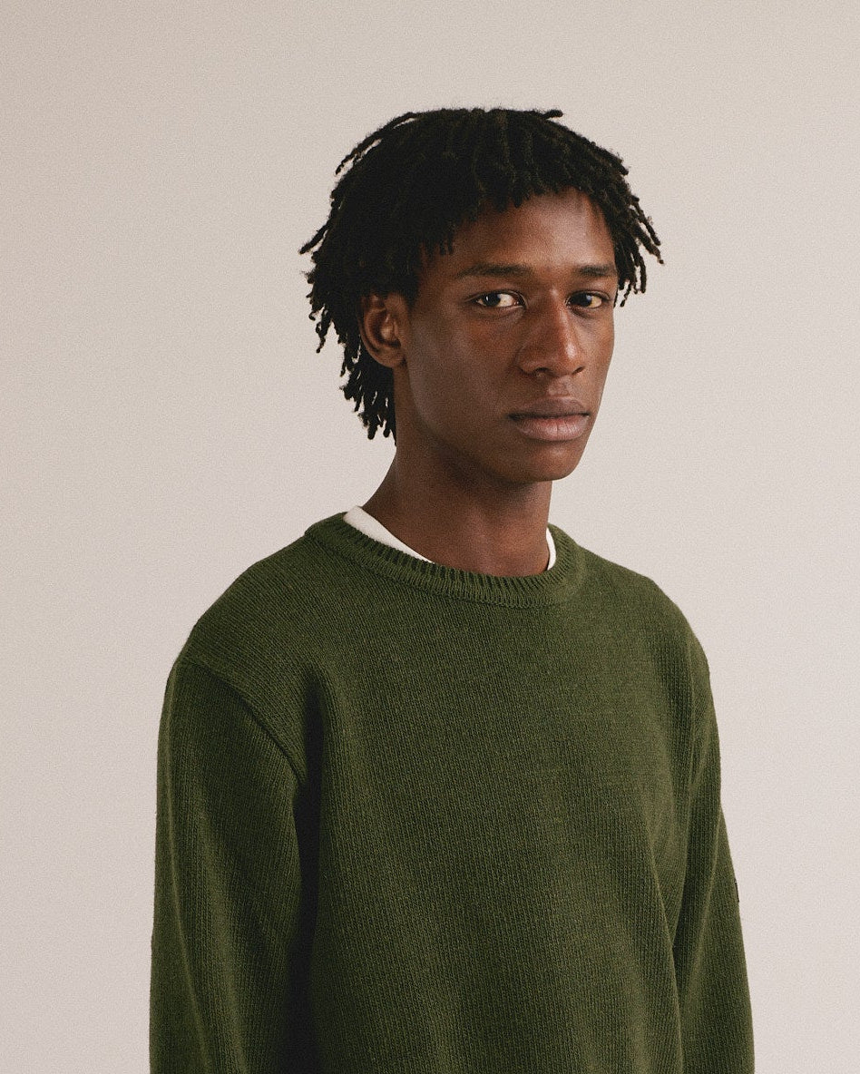 Hombre joven vistiendo jersey verde de punto con estilo minimalista y look casual moderno.