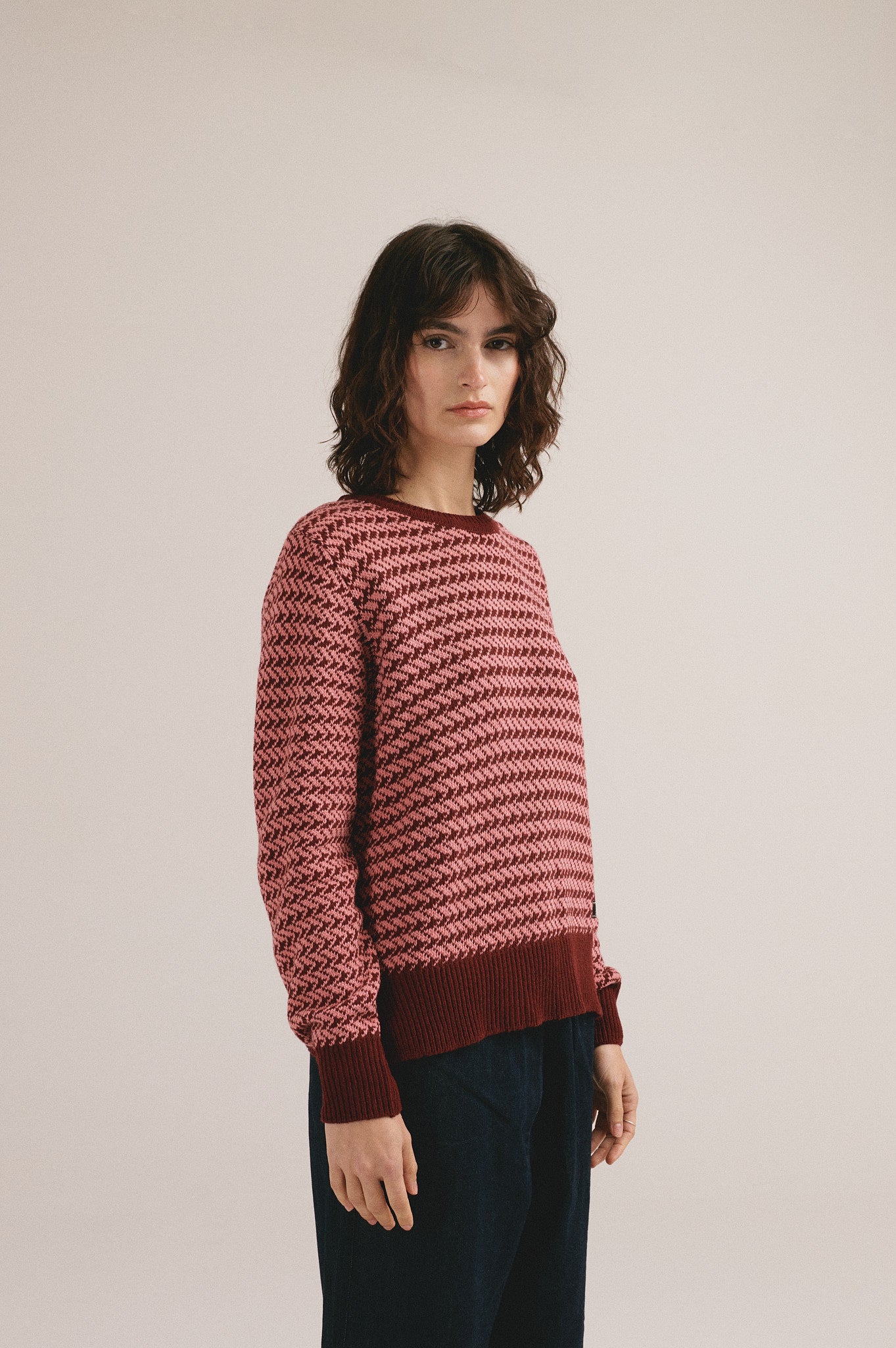 Modelo femenina con suéter de punto en tonos rojizos con diseño texturizado de IAIOS.