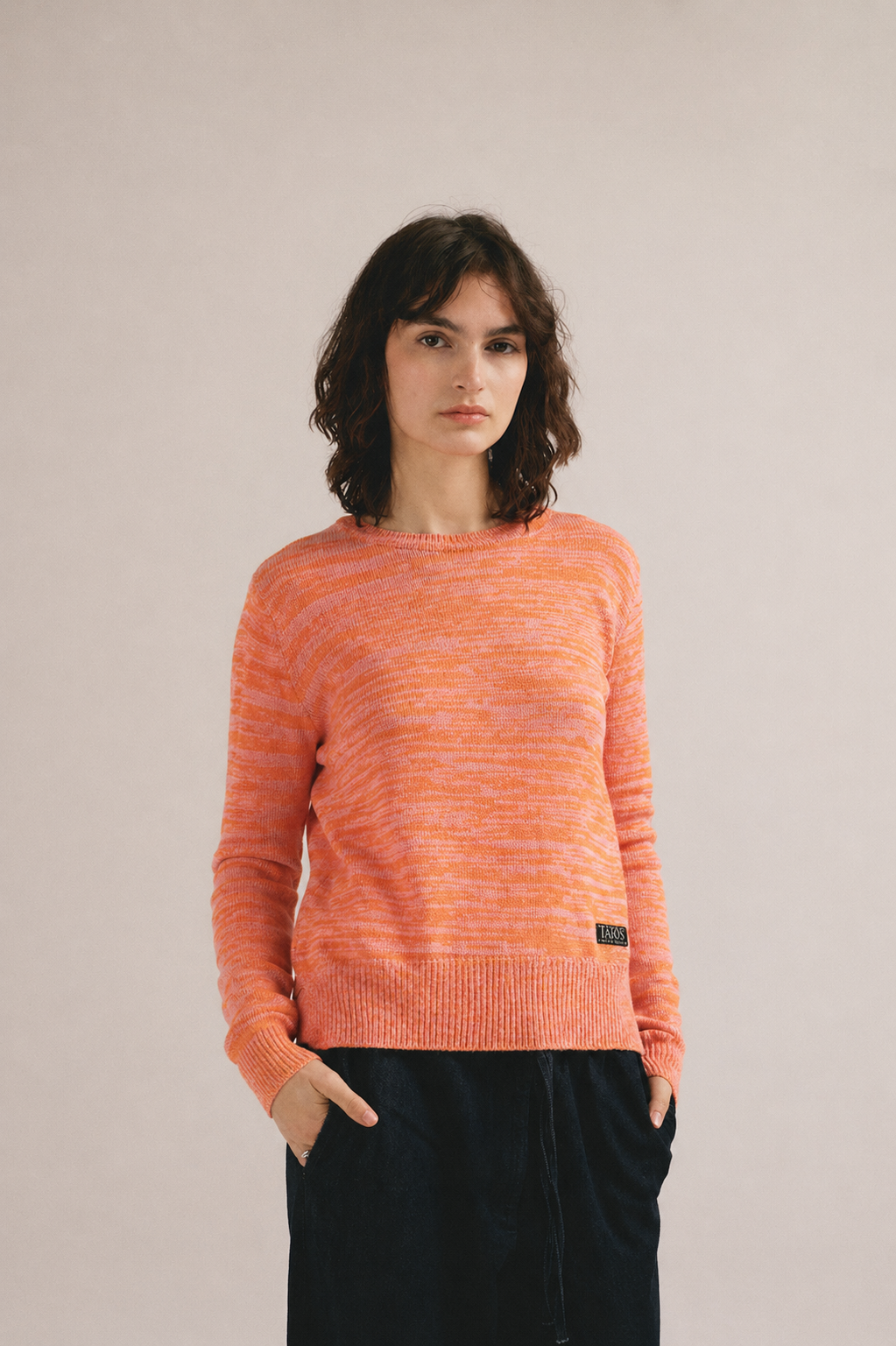 Modelo femenina con suéter de punto naranja con textura jaspeada y manga larga de IAIOS.