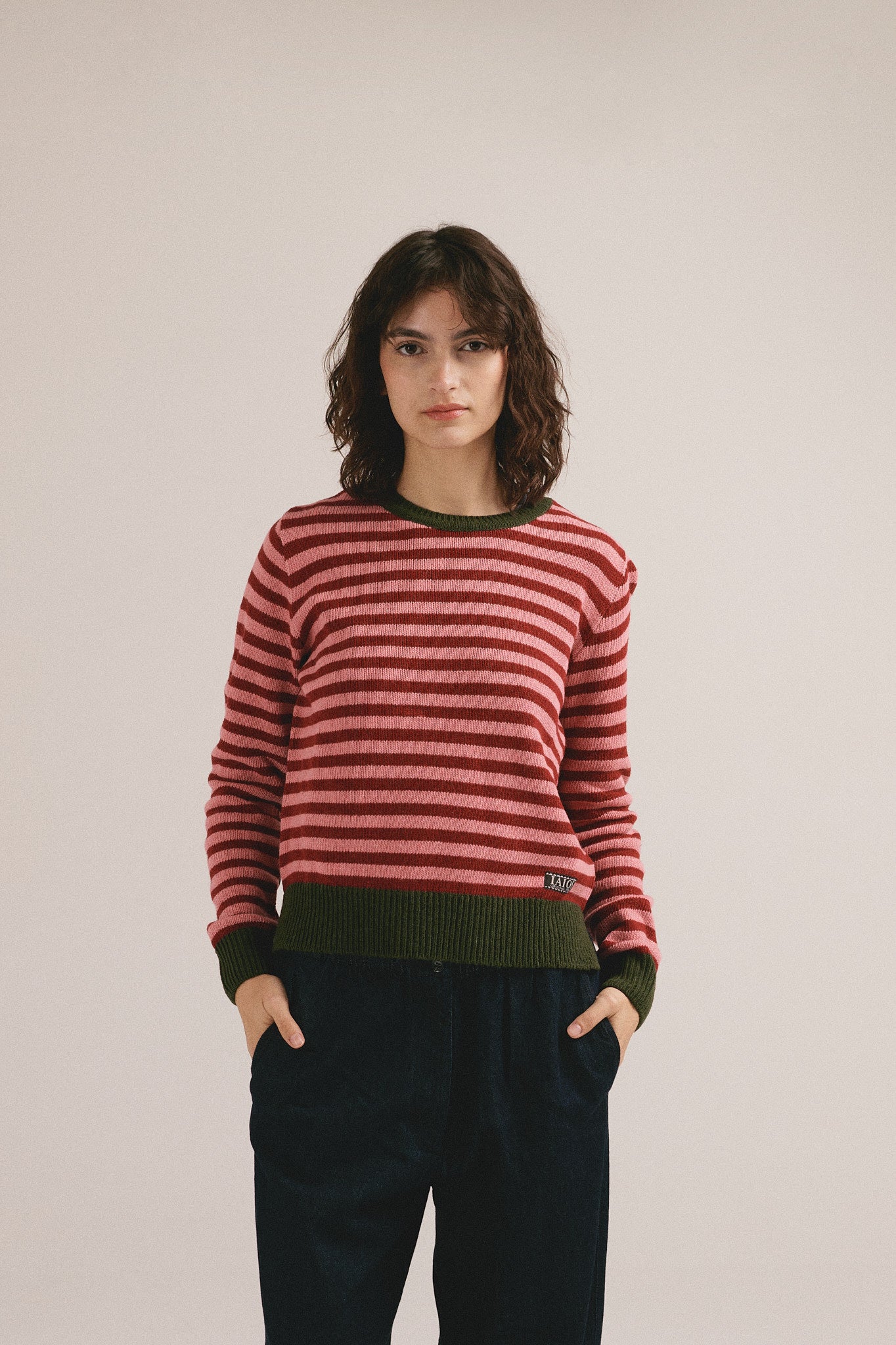 Mujer joven vistiendo jersey de punto a rayas rojas con estilo casual moderno y diseño ajustado.