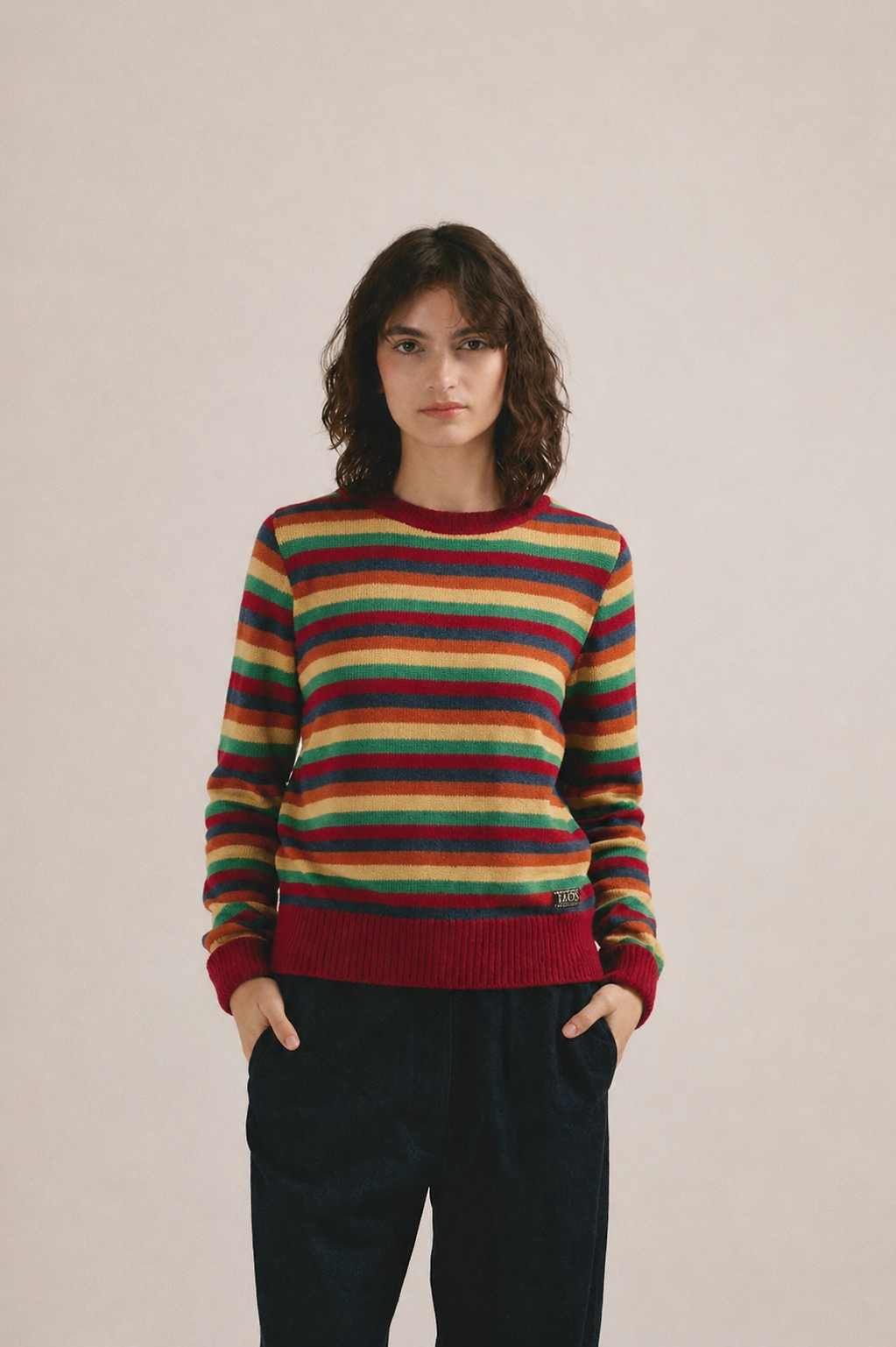 Mujer joven vistiendo jersey de punto a rayas multicolor con estilo casual moderno.