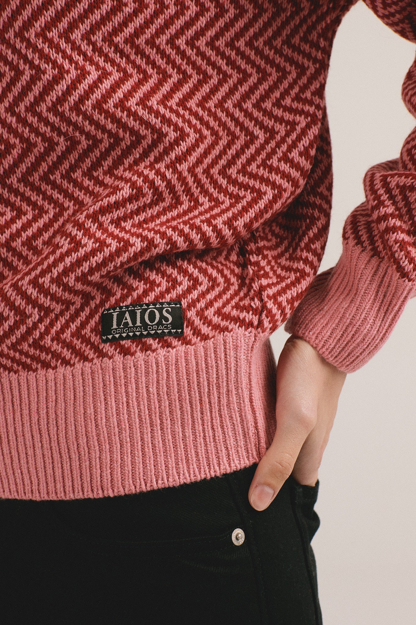 Detalle de la manga del suéter de punto para mujer en color rojo con diseño moderno de IAIOS, combinado con pantalón oscuro.