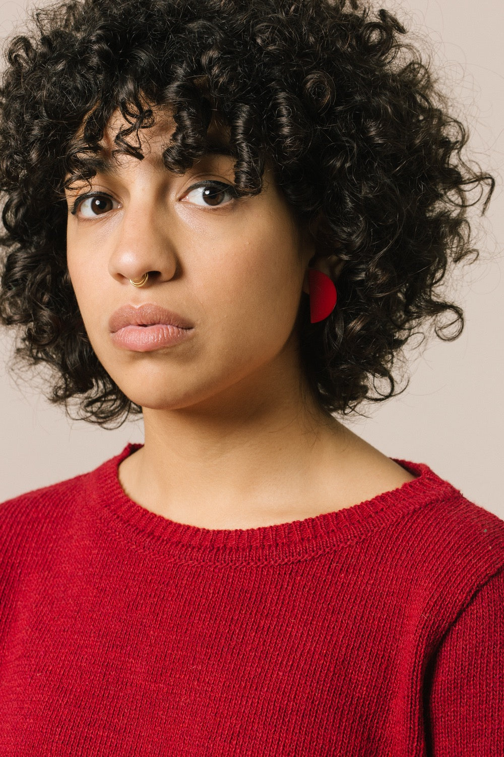 Retrato de la modelo con el jersey. Vemos que el color rojo favorece mucho y puede ser una nota de color en tu armario.