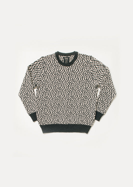 Men's or unisex sweater in black and white. The design of the sweater is a jacquard that makes spots that could resemble those of a zebra. 