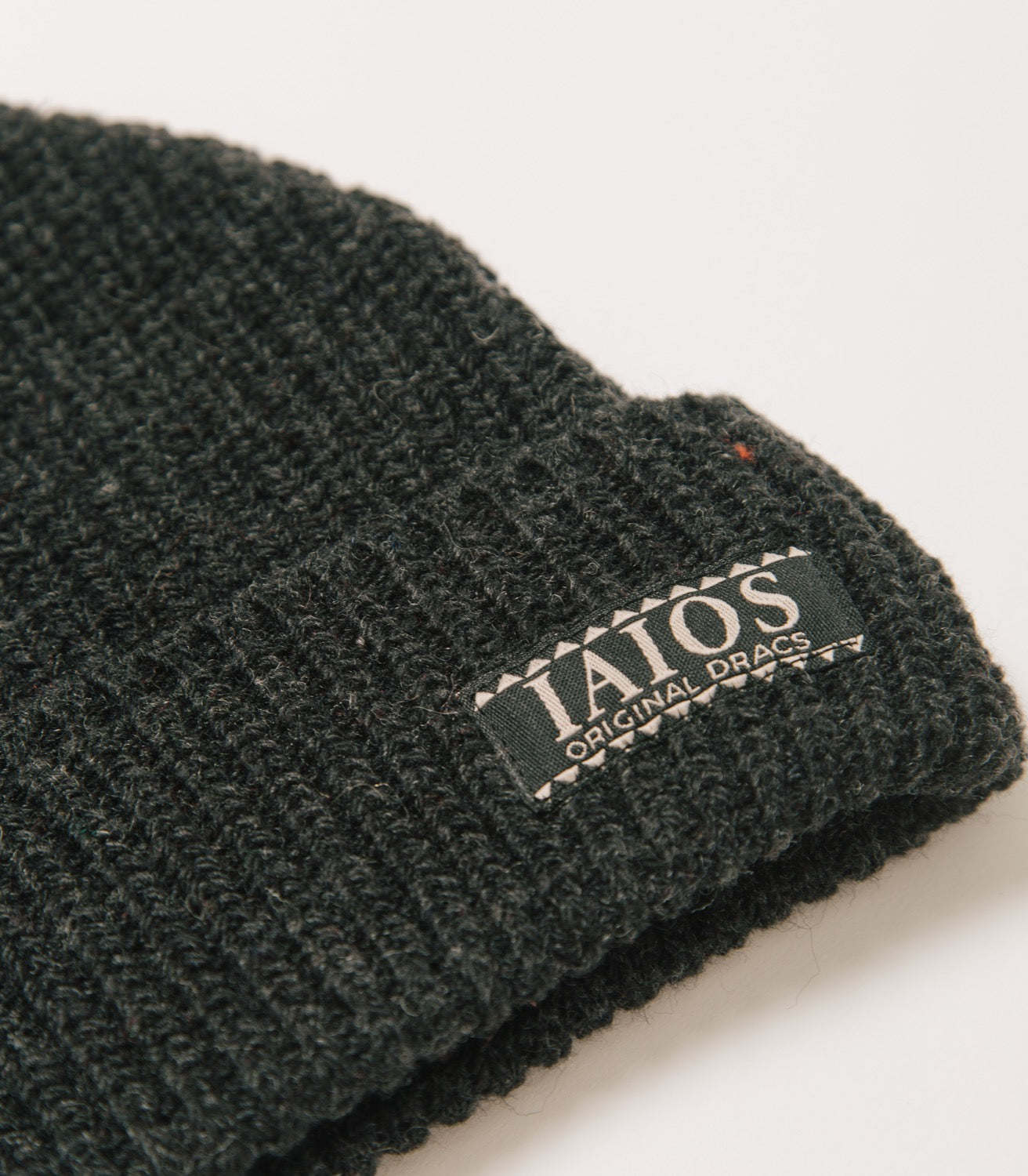 Detalle de la etiqueta IAIOS que lleva el gorro negro