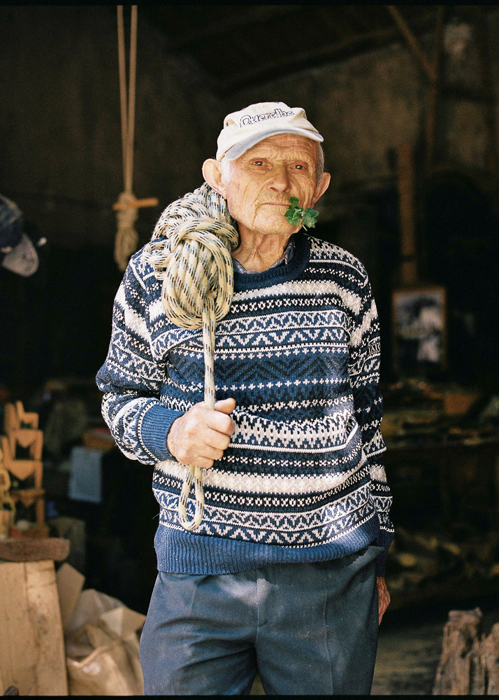 El abuelo lleva el jersey unisex IAIOS azul de estilo nórdico con tejido jacquard de cinco colores, moda sostenible hecha en Catalunya (España) con hilo reciclado.