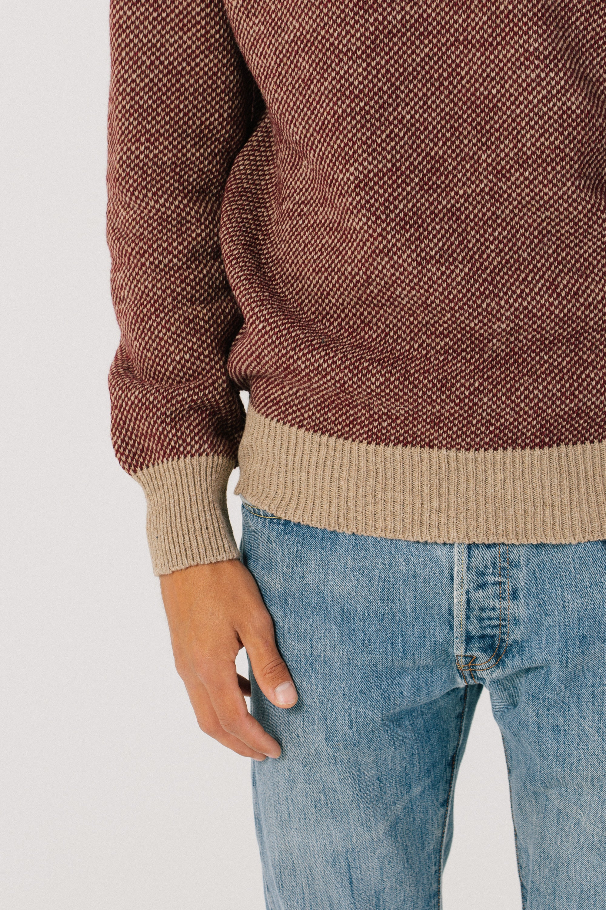 Detalle del bajo del jersey. Los puños son de color camel. Jersey unisex IAIOS rojo y camel en punto grano de arroz, moda sostenible, fotografía en plano (flat lay), hecho en Catalunya (España) con hilo reciclado.