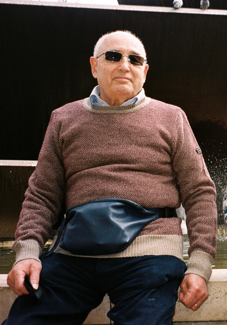 El abuelo lleva el jersey unisex IAIOS rojo y camel en punto grano de arroz, moda sostenible hecha en Catalunya (España) con hilo reciclado, ideal para invierno.