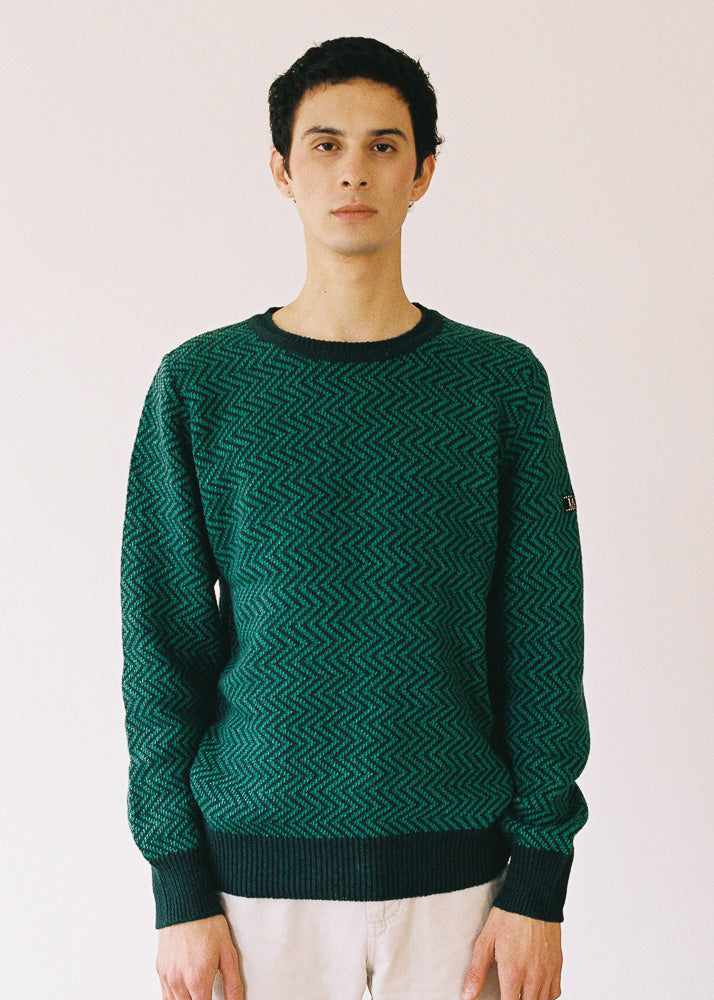 El modelo lleva el jersey IAIOS verde unisex con patrón zigzag, moda sostenible elaborada en talleres de Catalunya (España) con hilo reciclado.